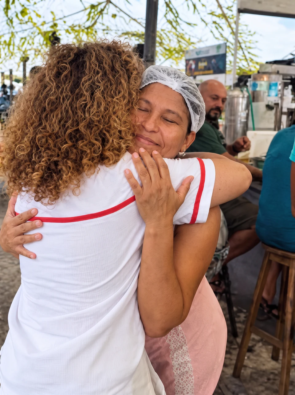 Úrsula abraçando uma trabalhadora em um mercado